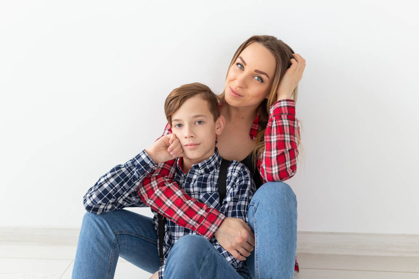 Familie, moeders dag en tiener concept - portret van de moeder en zoon zittend op de vloer - Foto, afbeelding