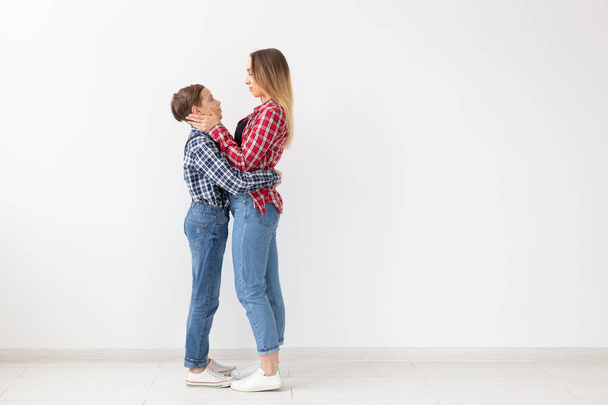 Concepto de familia, moda y día de la madre - Madre abrazar a su hijo sobre fondo blanco con espacio de copia
 - Foto, Imagen