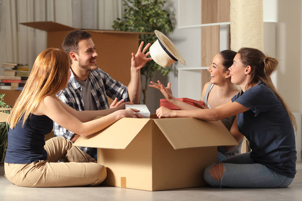 Happy roommates joking unboxing belongings moving home - Foto, imagen