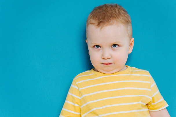 Portrait of cute shy blond little toddler boy in T-shirt - Photo, Image