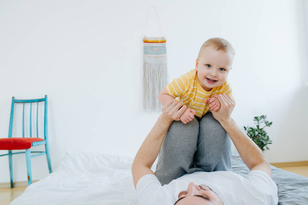 Young father is playing with his little toddler baby in parents bedroom - Foto, immagini