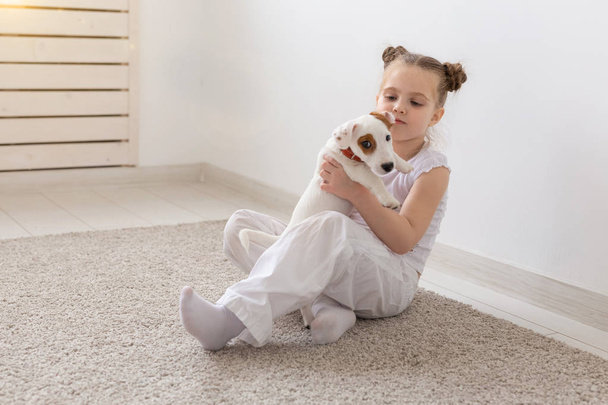 İnsanlar, Evcil hayvan ve hayvan kavramı - beyaz arka plan ve holding köpek yavrusu Jack Russell Terrier üzerinde katta oturan küçük kız - Fotoğraf, Görsel