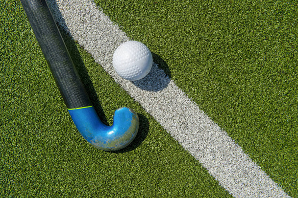 Veldhockeystick en bal op het groene veld - Foto, afbeelding