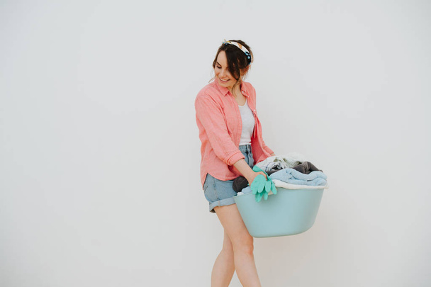 Young happy woman with laundry basin full of washed towels - Foto, Bild