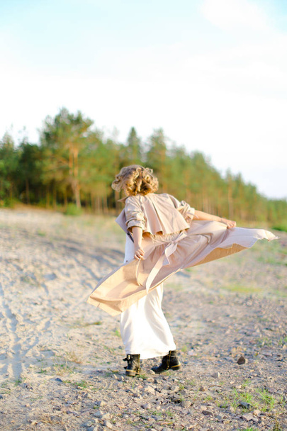 Young woman turning around on sand with trees in background. - Valokuva, kuva