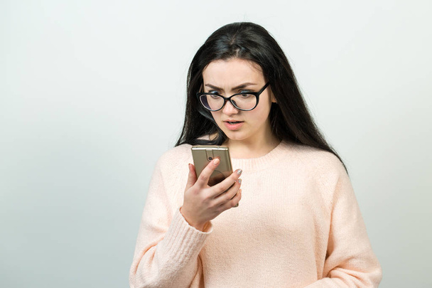 Piękna młoda biała kobieta nosi okulary za pomocą smartfona na białym tle - Zdjęcie, obraz
