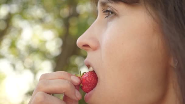 glückliches Mädchen, das im Sommer Erdbeeren im Garten isst. leckeres Erdbeerdessert. schönes Mädchen, das saure Erdbeerfalte isst und lächelt. Nahaufnahme. Vitamin- und Beerendiät für Frauen. - Filmmaterial, Video