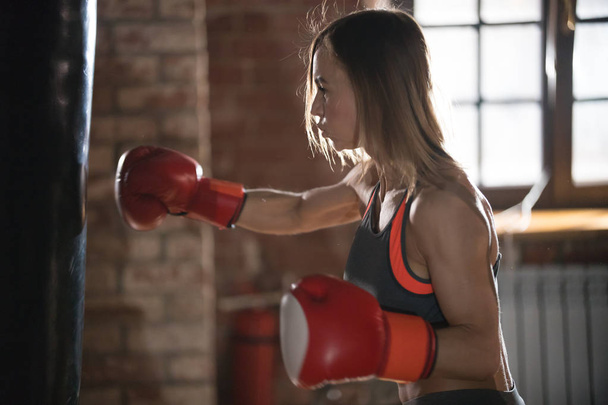 Agresywna kobieta bokser uderzając worek wykrawania w siłowni na treningu - Zdjęcie, obraz