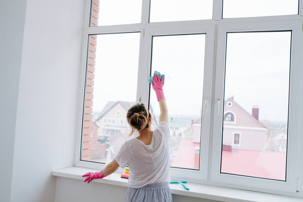 Young woman is cleaning plastic window door with wet cloth - Fotó, kép