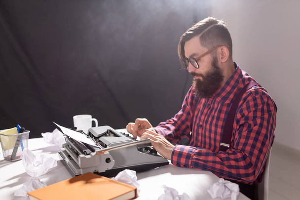 People and technology concept - World day of the writer, handsome man with glasses, dressed in plaid shirt, working on typewriter - Foto, afbeelding