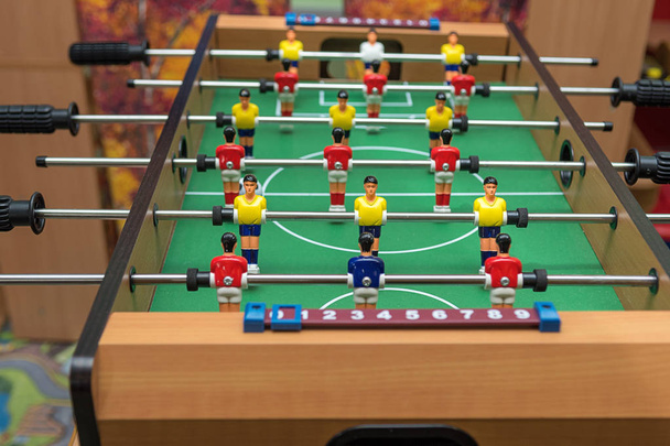 テーブルホッケー付きのテーブル。選手たちは黄色と赤の服を着ている。子供と大人のためのテーブルホッケーのおもちゃ. - 写真・画像