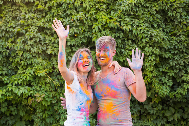 Holiday, holi e people concept - Coppia felice che si diverte con polvere multicolore sul viso
 - Foto, immagini