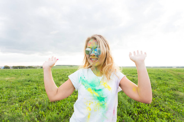 Spaß, Freude, Menschen und Urlaubskonzept - junge fröhliche Frau bei Holi-Paint-Party - Foto, Bild