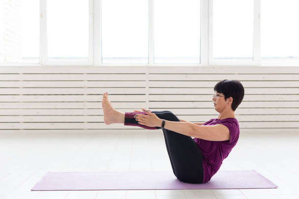 Yoga, conceito de pessoas - uma mulher de meia-idade fazendo um ioga no ginásio
 - Foto, Imagem