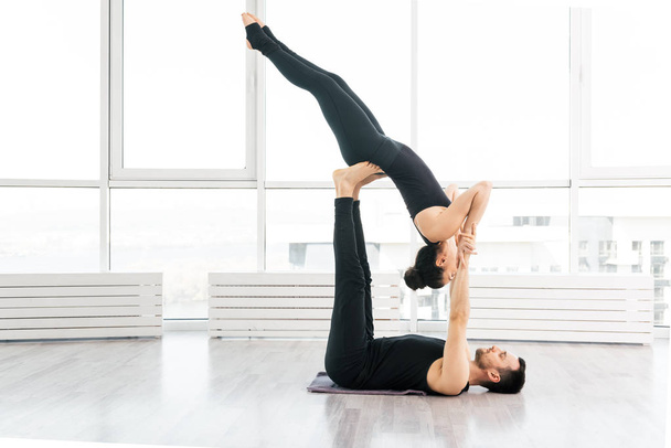 Positive woman practice acro yoga with man partner at studio - 写真・画像