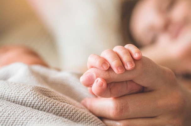 Female hand holding her newborn baby hand. Mom with her child. Maternity, family, birth concept - Fotó, kép