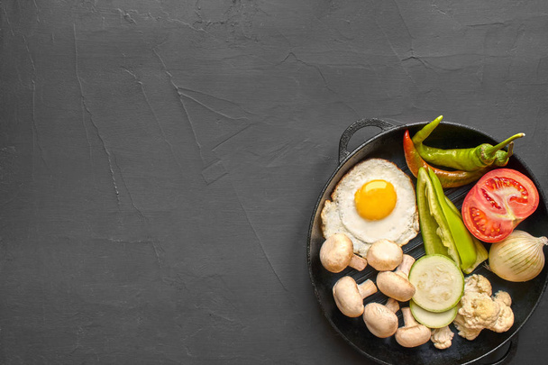 Top view of a fresh vegetables and scrambled eggs. Black background with copyspace. - Foto, Imagen