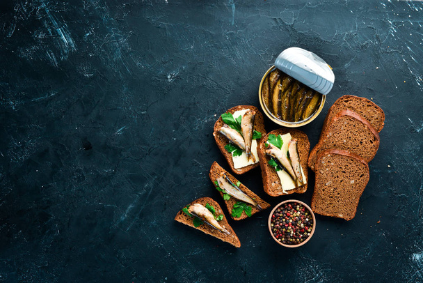 Sandwich with Sprat. Sprat in oil. On a black background. top view. Free copy space. - Zdjęcie, obraz