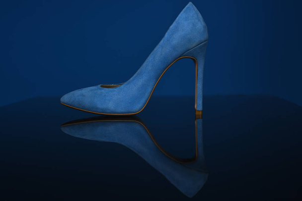 High heel fashion shoes. Comfortable women shoe are on dark mirror floor on blue background. Concept of advertising shoes which are on sale. Cinderellas dream shoes for every woman. Female fashion - Photo, Image