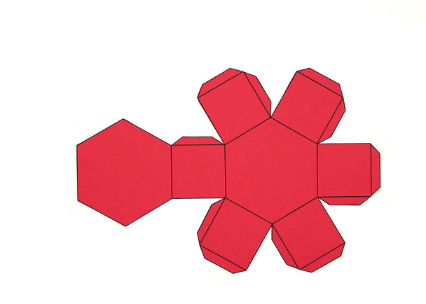 Forma geométrica cortada de papel rojo y fotografiada sobre fondo blanco.Prisma hexagonal. 2D moldeable para formar una forma tridimensional o sólida
. - Foto, imagen