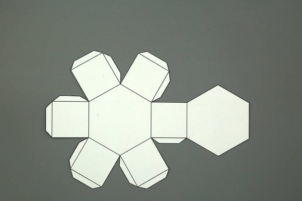 Forma geométrica cortada de papel y fotografiada sobre fondo blanco.Prisma hexagonal. 2D moldeable para formar una forma tridimensional o sólida
. - Foto, Imagen