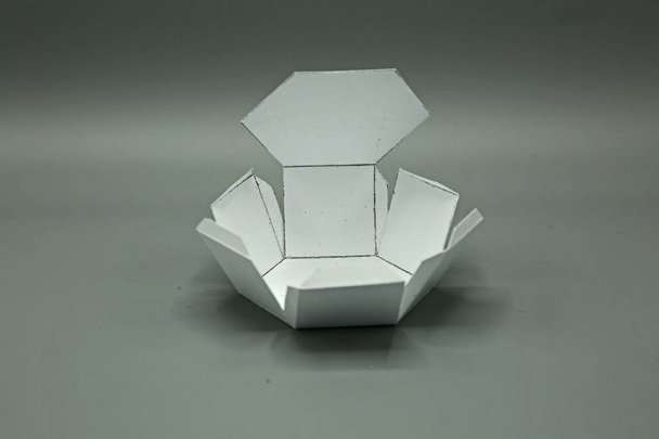 geometrische Form aus Papier ausgeschnitten und auf grauem Hintergrund fotografiert. Sechseckiges Prisma. 2d formbar, um eine 3-dimensionale Form oder einen Körper zu bilden. - Foto, Bild