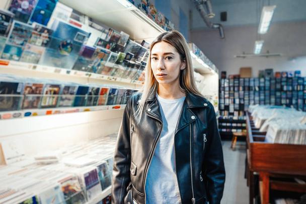 Young attractive woman choosing vinyl record in music record shop. - 写真・画像
