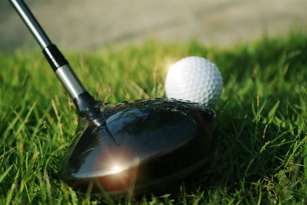 Bola de golfe na grama verde em belo campo de golfe ao pôr do sol de volta
 - Foto, Imagem
