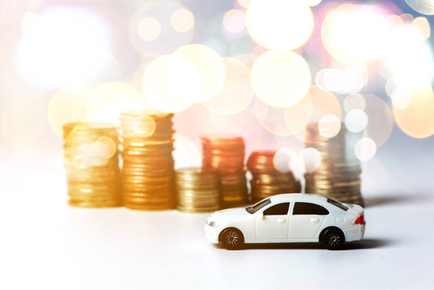 White car with stacked coins on white background in selective focus, Concept : car, money, financial, business. - Fotó, kép