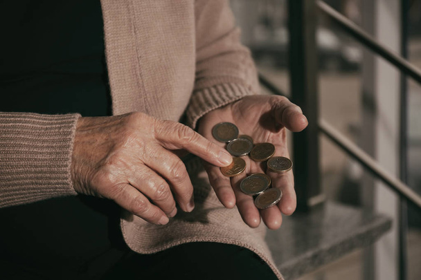 Poor senior woman with coins on stairs, closeup - Fotoğraf, Görsel