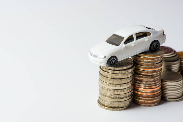 White car with stacked coins on white background in selective focus, Concept : car, money, financial, business. - Zdjęcie, obraz