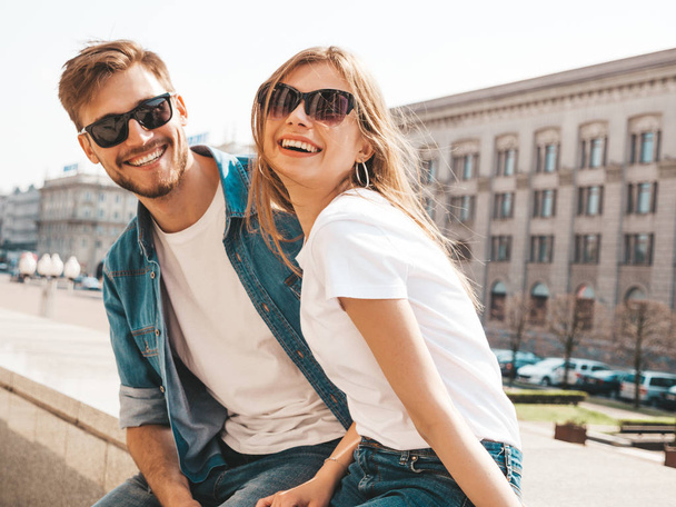 Smiling beautiful girl and her handsome boyfriend in casual summer clothes. Happy cheerful family having fun on the street background in sunglasses - Photo, image