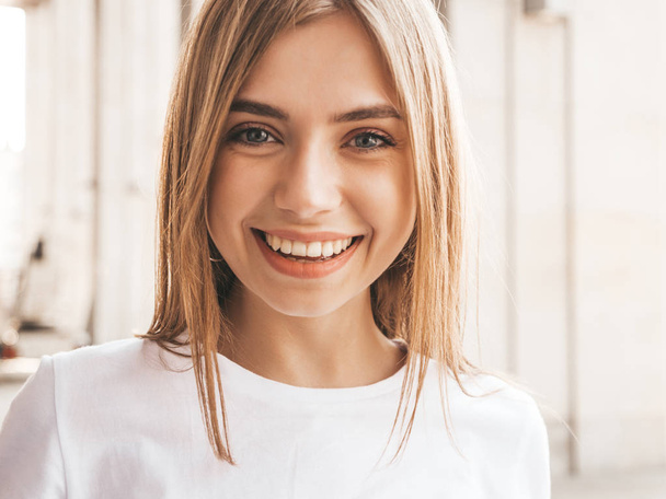 Portrait of beautiful smiling blond model dressed in summer hipster  clothes. Trendy girl posing in the street background. Funny and positive woman - Foto, afbeelding