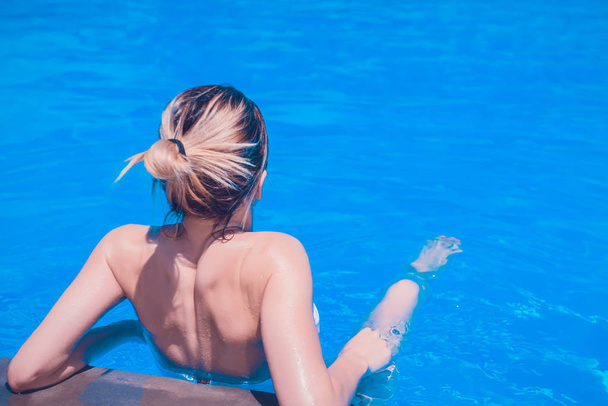 όμορφη νεαρή γυναίκα ξεκουράζεται στην πισίνα σε μια ηλιόλουστη μέρα - Φωτογραφία, εικόνα