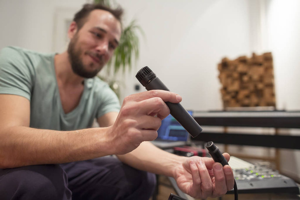 Musicien dans le studio de musique maison branchant le microphone et testant
. - Photo, image