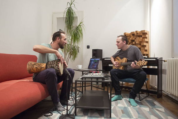 Deux musiciens jouant des instruments dans un studio de musique maison
. - Photo, image