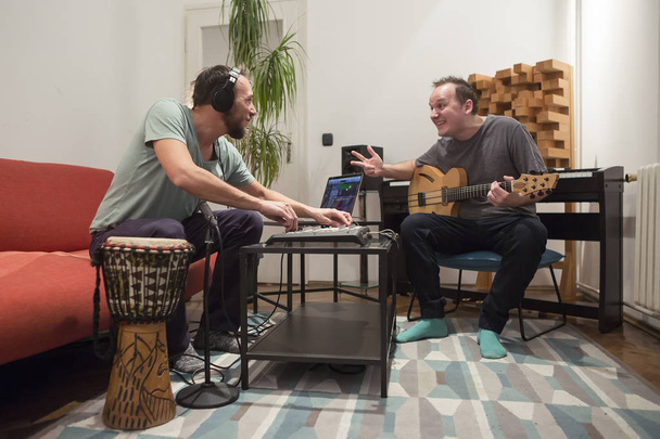 Dva hudebníci hrající nástroje v domácím hudebním studiu. - Fotografie, Obrázek