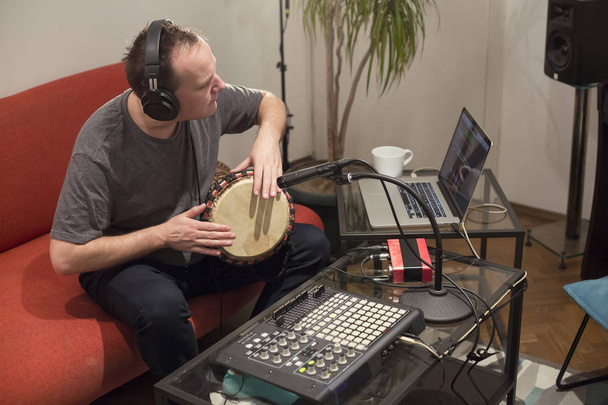ホームミュージックスタジオでジャンベドラム楽器を演奏するミュージシャン. - 写真・画像