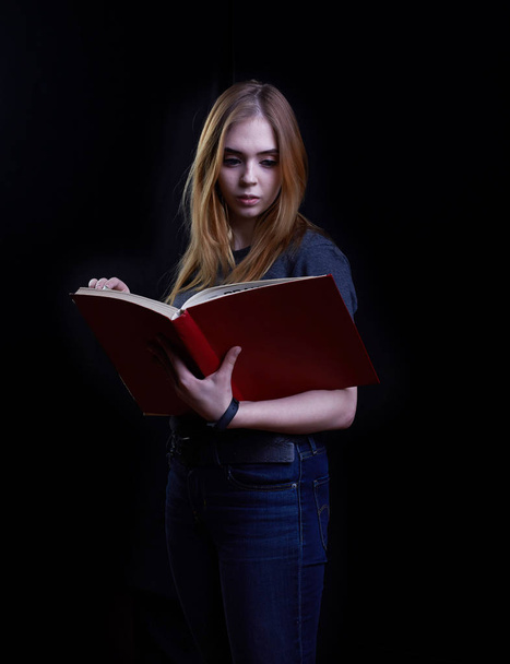young girl reading a book on a black background - Фото, изображение