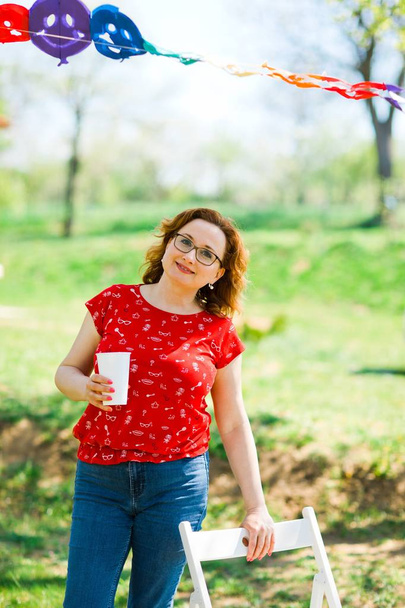 Mulher de vestido vermelho bebendo na festa do jardim
 - Foto, Imagem