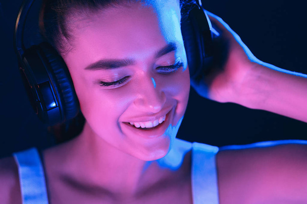 DJ In Club. Woman in headset illuminated by neon lights - Foto, Bild