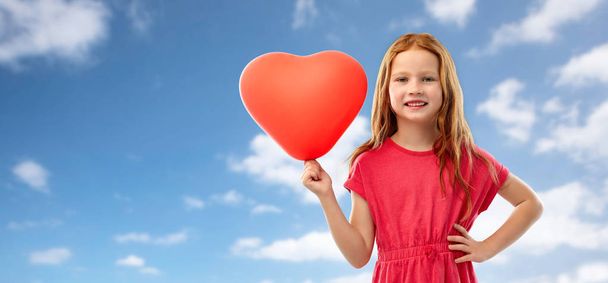 happy red girl with heart shaped balloon over sky - Фото, зображення