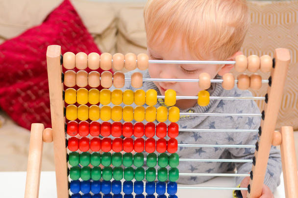 Kinder lernen zu zählen. Junge benutzt Abakus, um Mathe zu lernen - Foto, Bild