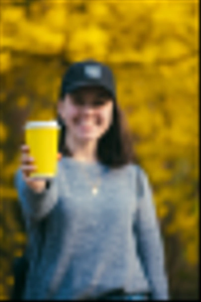 young pretty woman holding and showing yellow coffee paper cup - Fotoğraf, Görsel