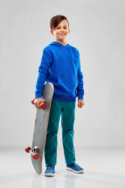 smiling boy in blue hoodie with skateboard - Zdjęcie, obraz