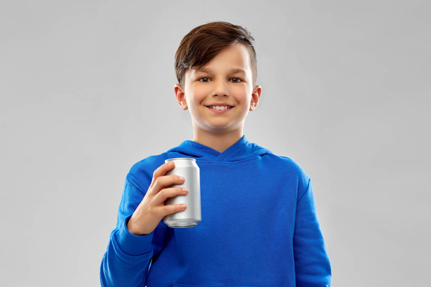 smiling boy in blue hoodie holding can drink - Foto, afbeelding