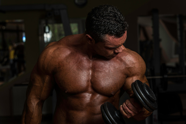 Body builder doing heavy weight exercise for biceps with dumbbell - Foto, Imagem