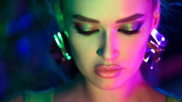 Woman wearing jewelry in colorful bright lights - Foto, imagen