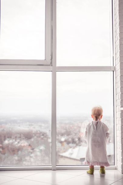 Lindo niño mirando a la ventana grande
 - Foto, Imagen
