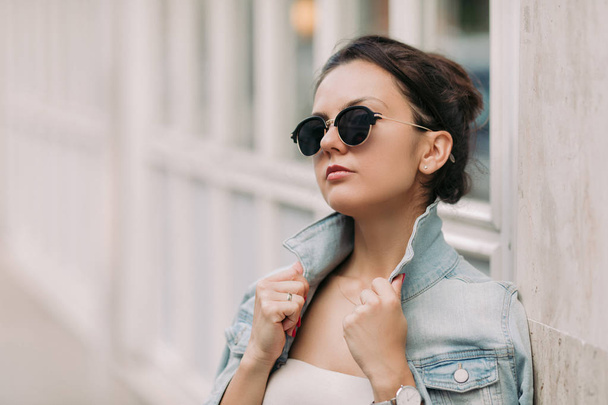 attractive woman in sunglasses and white dress walks through the city streets on a sunny day - Foto, afbeelding